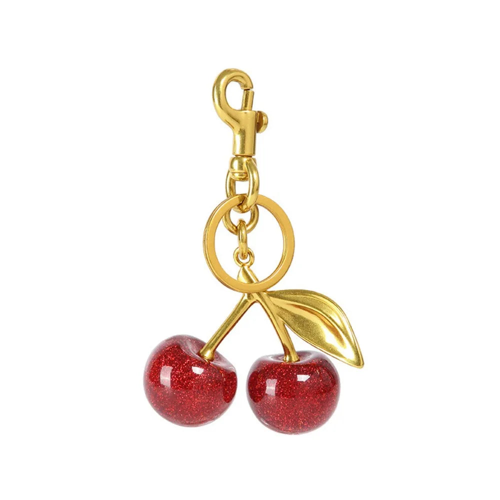 Gold and red cherry-shaped keychain on a white background
