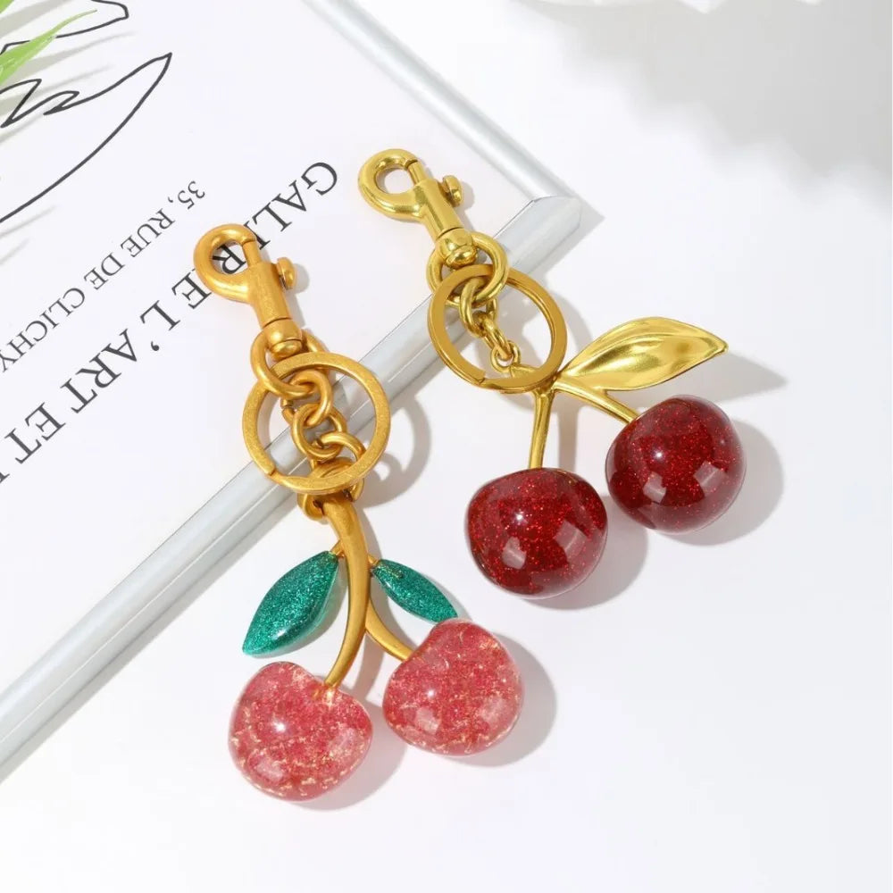 Cherry-shaped keychain with gold accents on a white surface