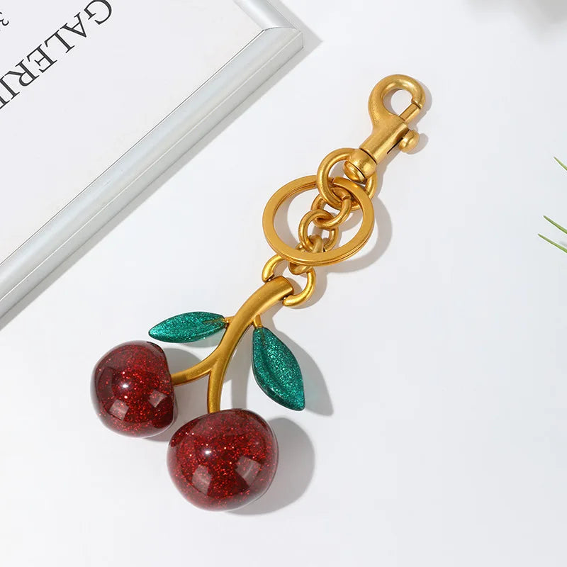 Gold keychain with red cherries on a white background