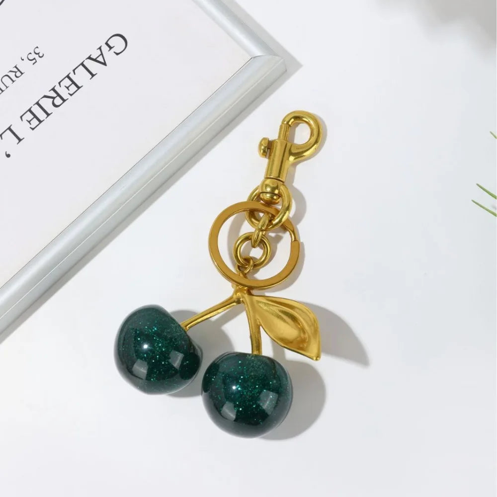 Gold and green cherry-shaped keychain on a white background