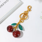 Gold keychain with red cherries on a white background